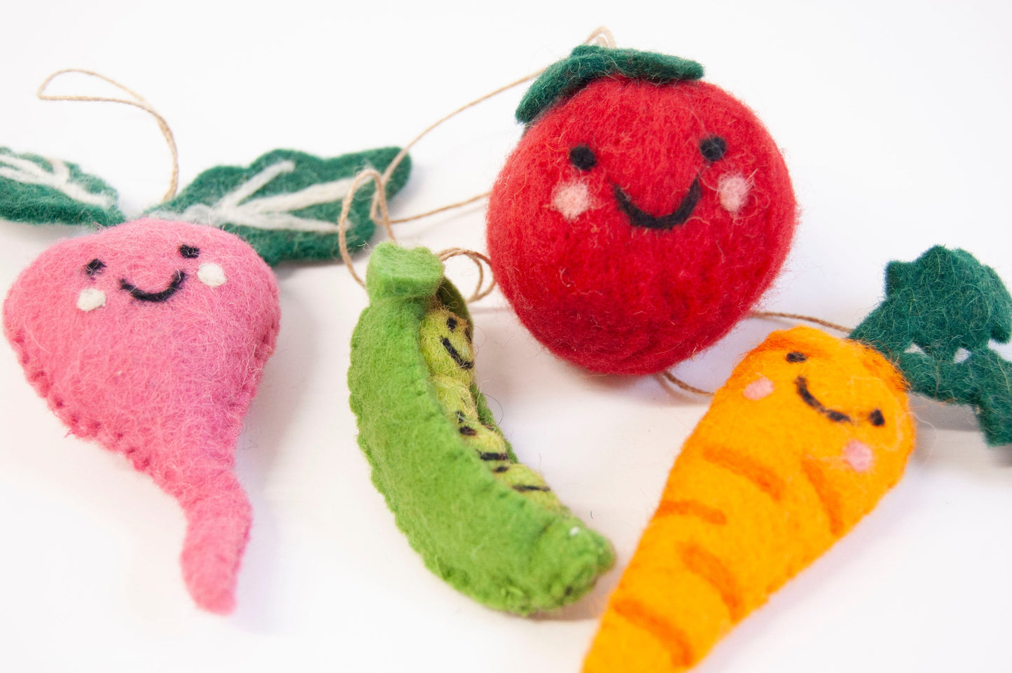 Felt vegetable ornaments with smiling faces on a white background