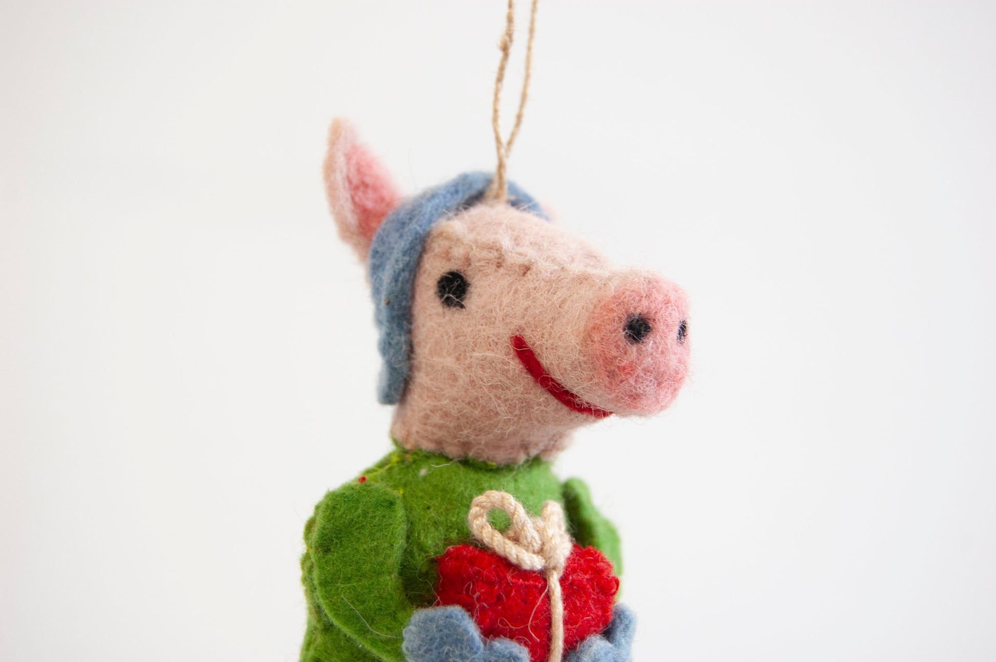 Felted pig ornament with a green sweater and red heart on a white background - ZWEIBIE