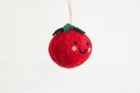 Felted red tomato ornament with a smiley face on a white background